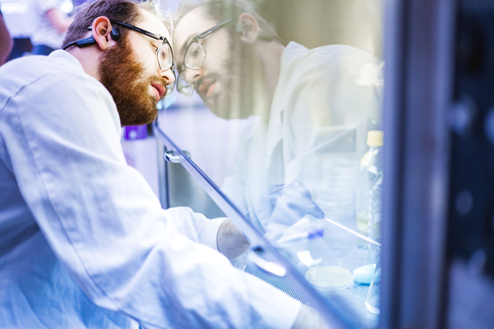 Student with glasses leaning on glass laboratory equipment